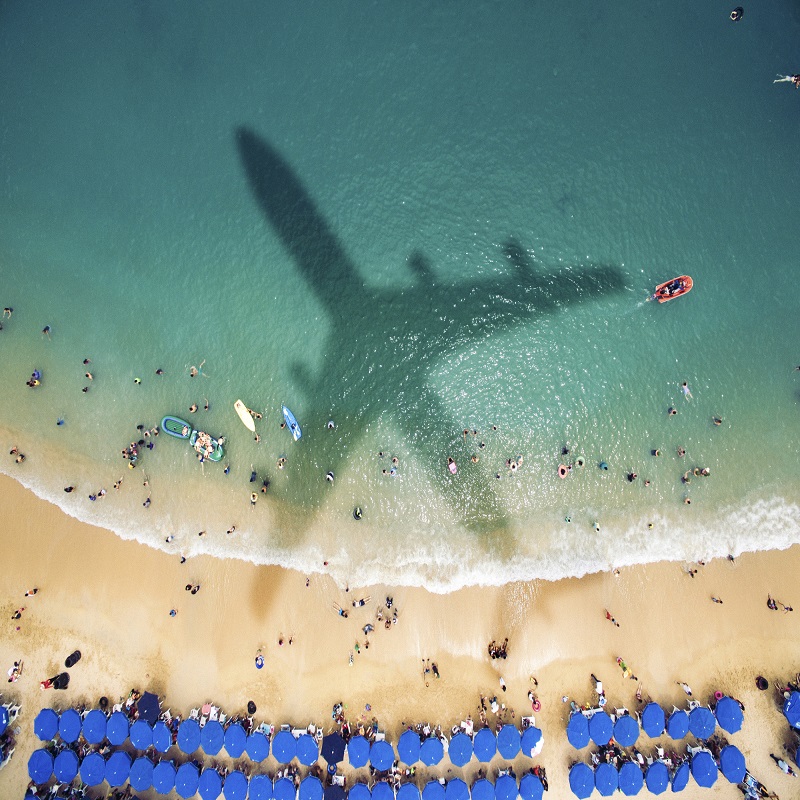 Airplane shadow over a crowded beach
