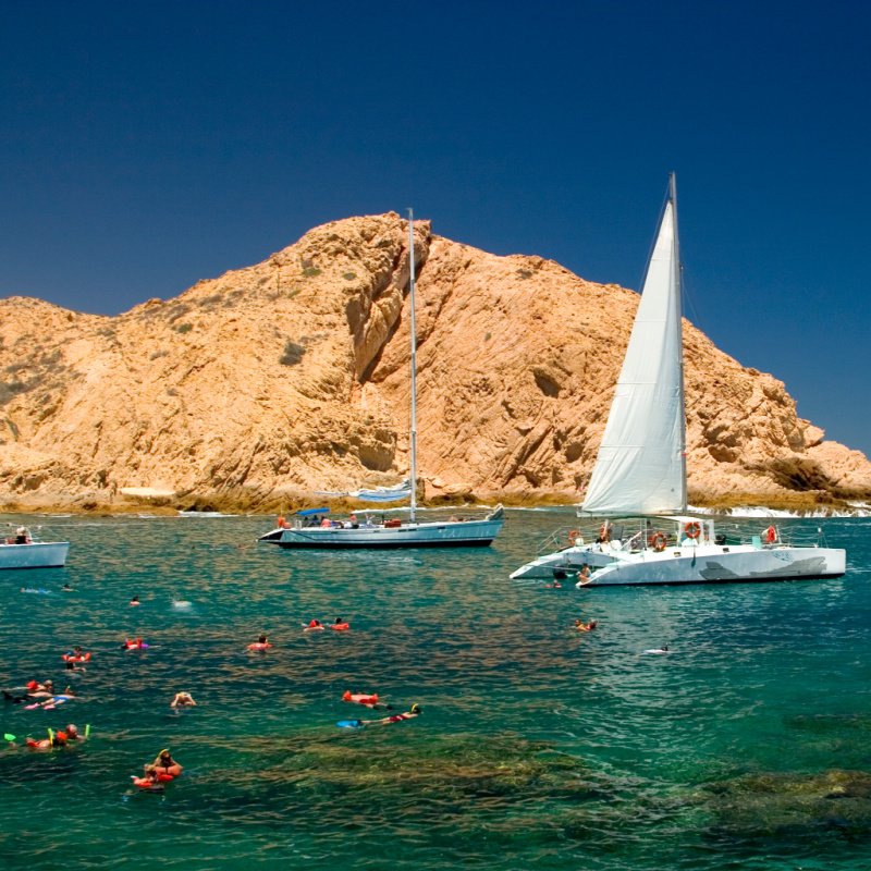Sail boats with tourists snorkeling around a Los Cabos beach