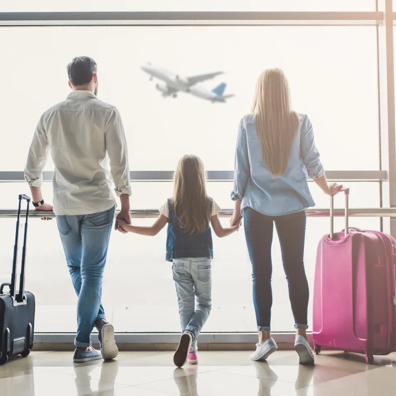 Couple at airport with child looking out the window.