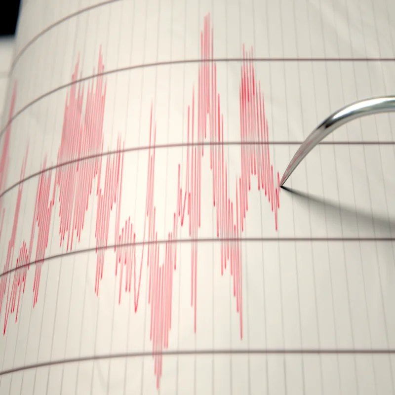A closeup of a seismograph machine needle drawing a red line on graph paper depicting seismic and eartquake activity - 3D render, Los Cabos concept