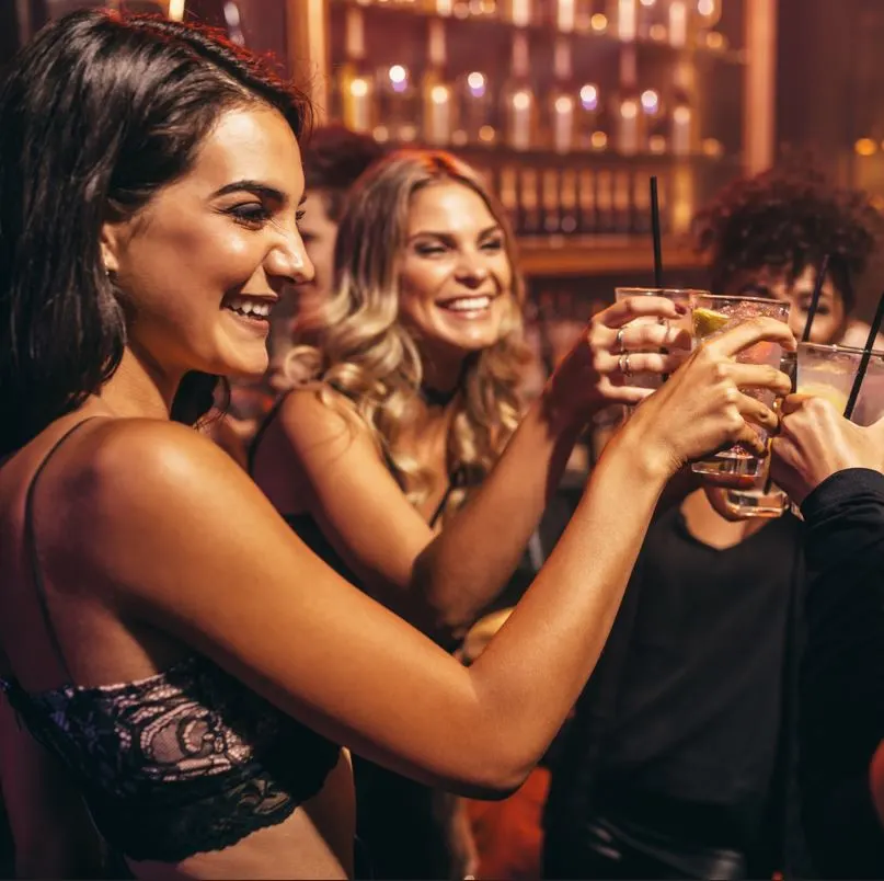 group of girls toasting drinks in a bar