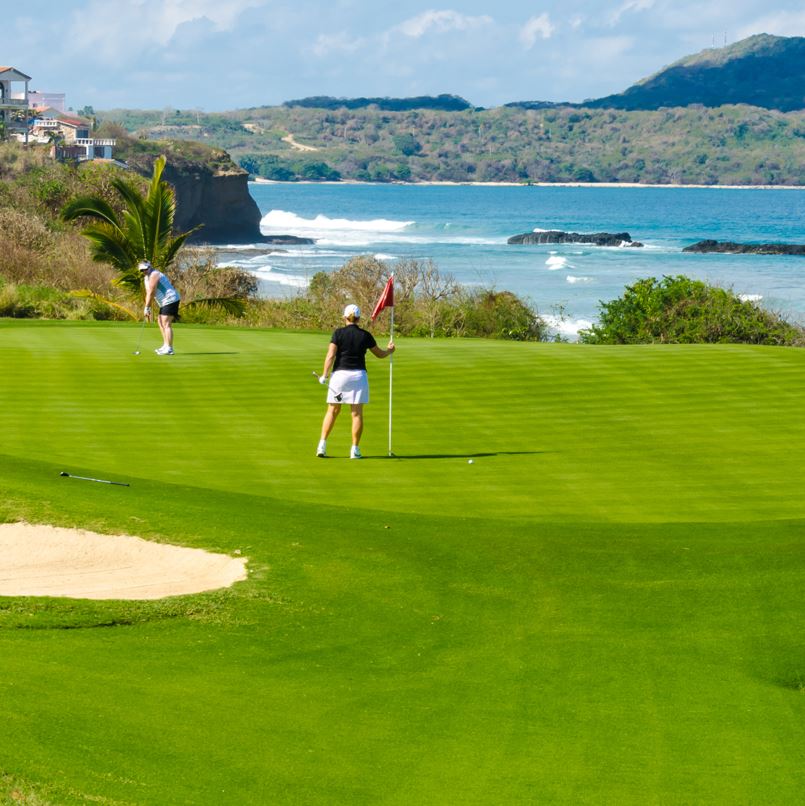 people golfing in a beach side course