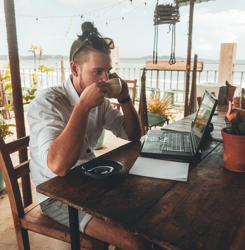 Man working on a laptop at a beach cafe