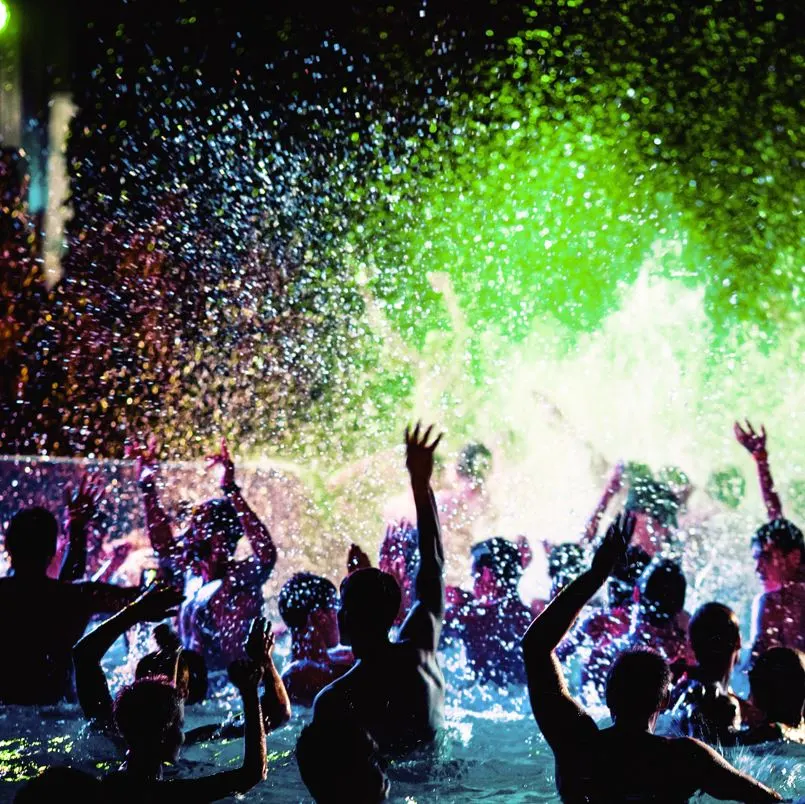 People partying in a swimming pool with neon lights