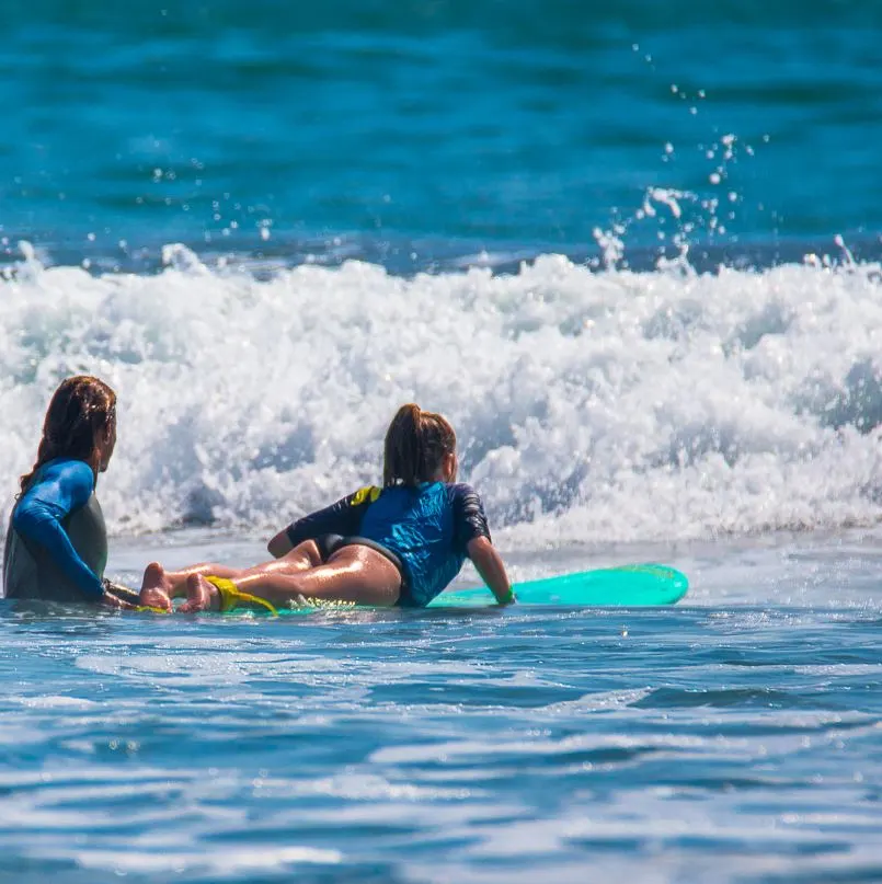 Surf instructor giving lessons to girl on surfboard