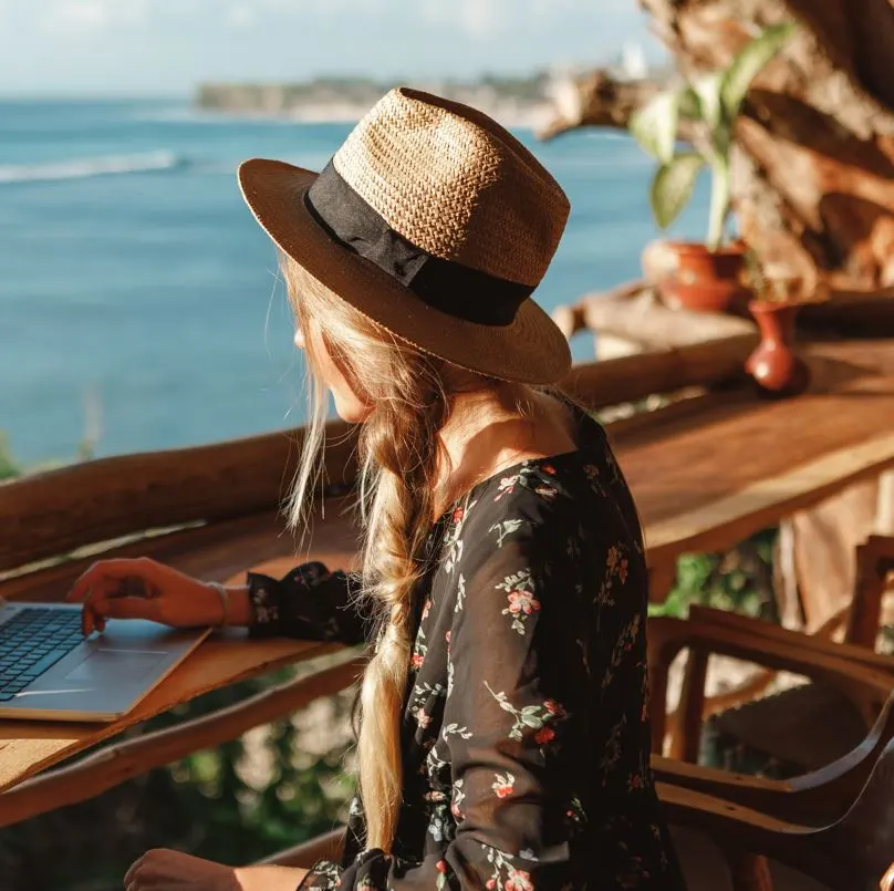 Woman working remotely at a beachside cafe