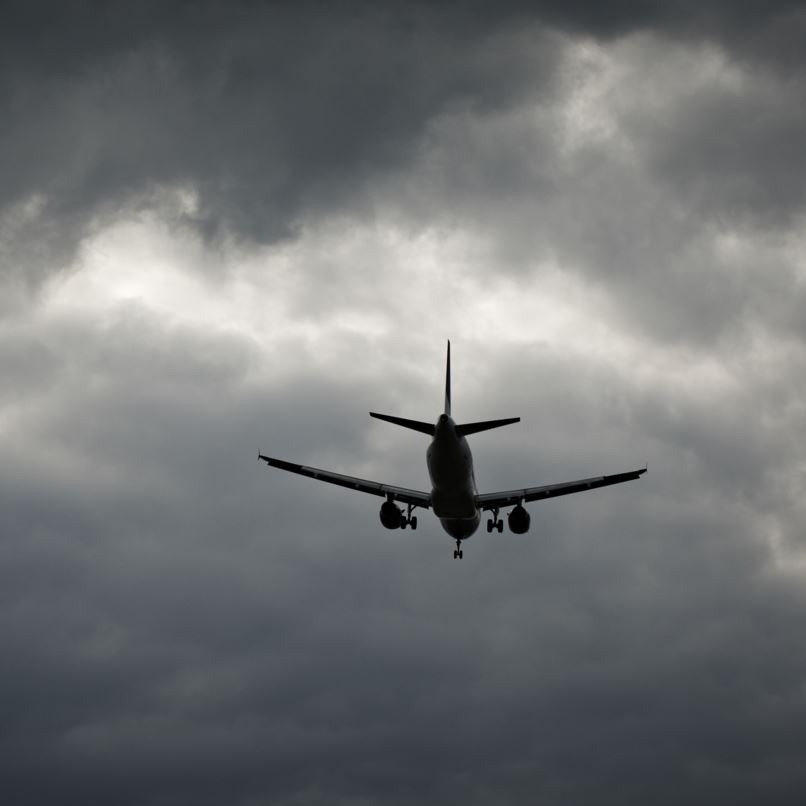 Airplane flying in a dark, clouded sky