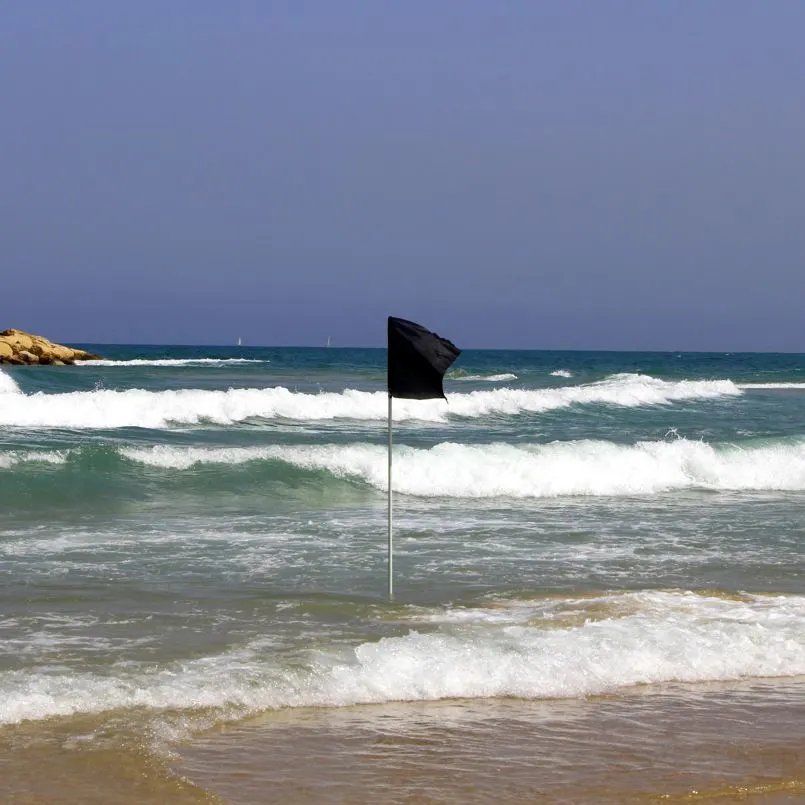 Black Beach Warning Flag on a Wavy Beach