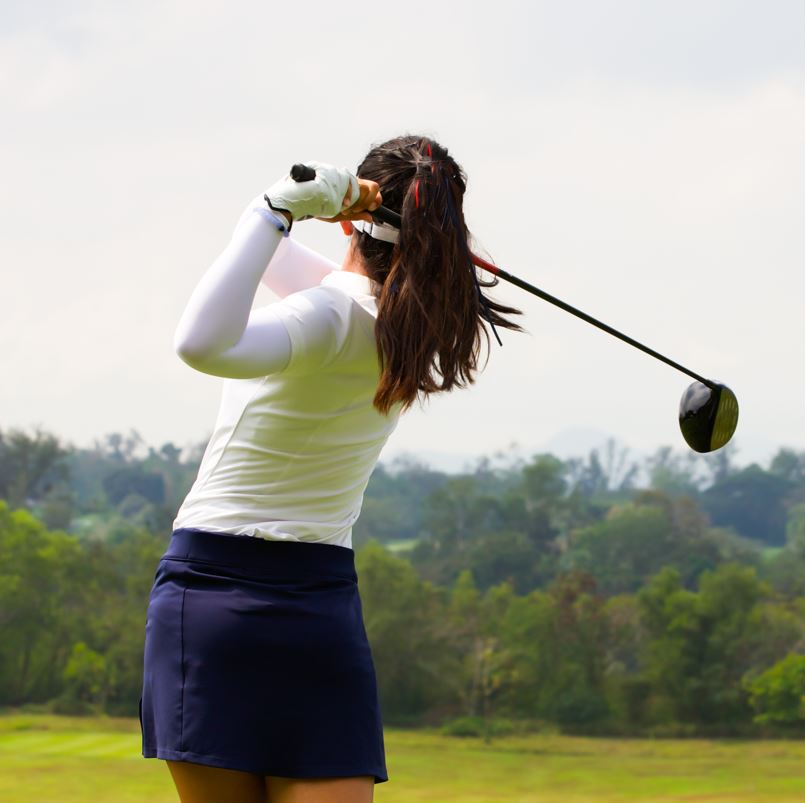 Woman golfer teeing off on course