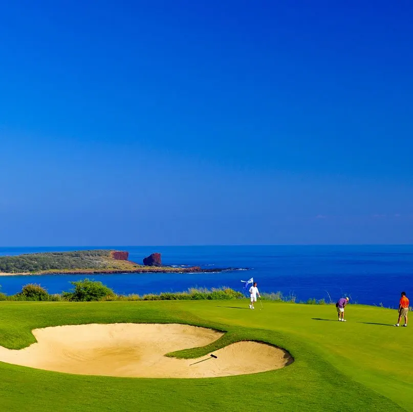 Golfers playing near the ocean