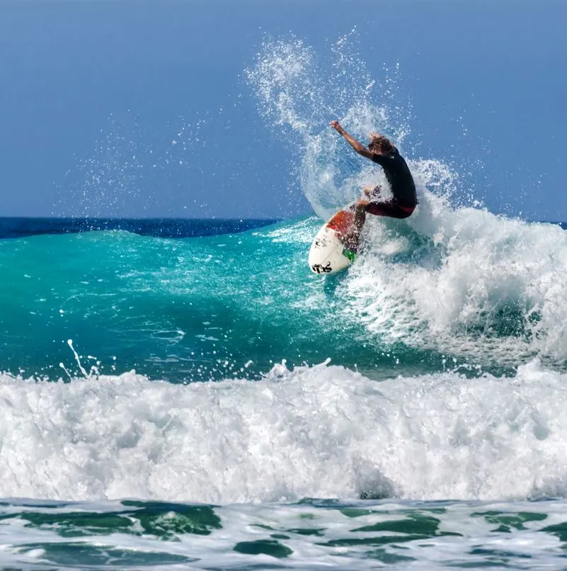 Surfer catching a wave in blue ocean