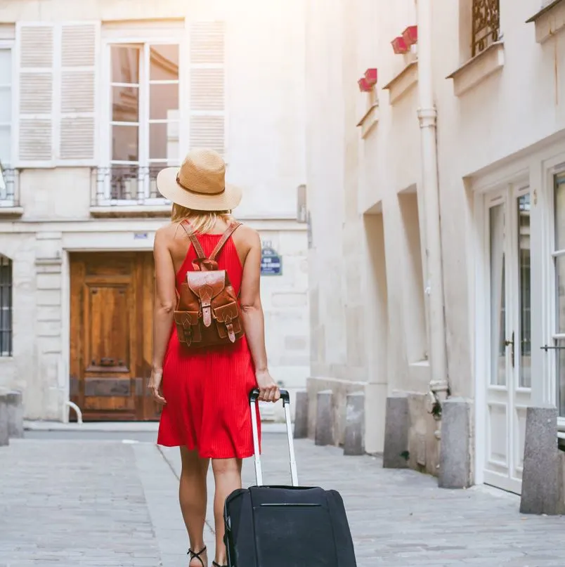 Woman with red dress with luggage and backpack