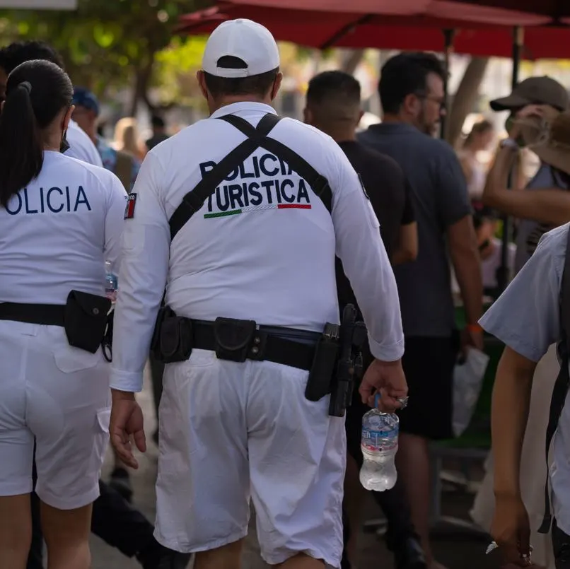 Tourist police walking through busy area with umbrellas