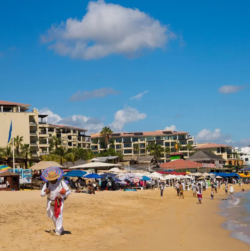 Vendor walking on crowded beach with umbrellas