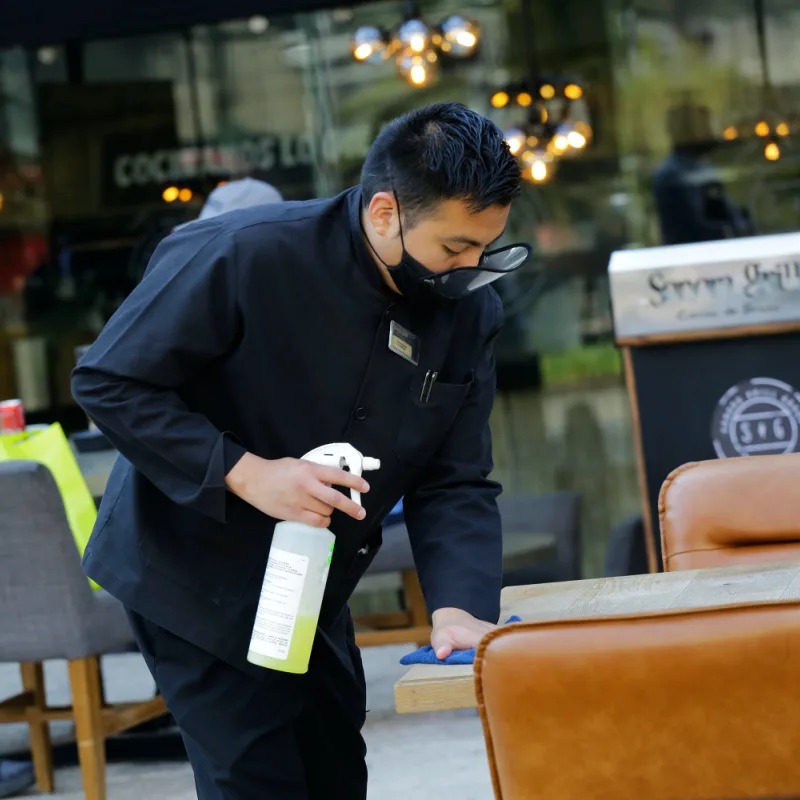 Waiter sanitizing restaurant table