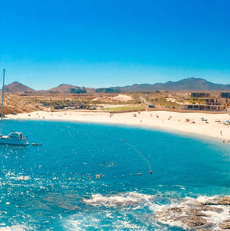 Beach with blue water and sand surrounded by rocks