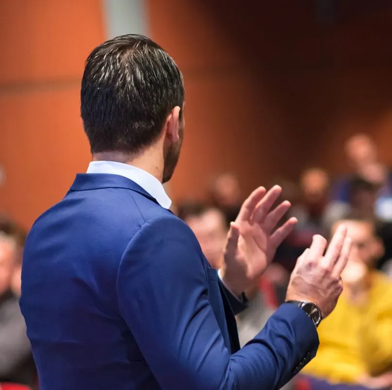 Person speaking to a crowd sitting