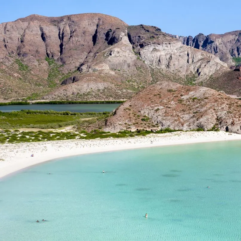 Clean blue waters with rock formations in the background