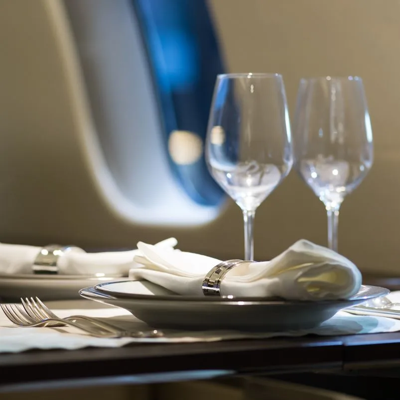 Dinner placement setting in plane with win glasses, plates, and silverware