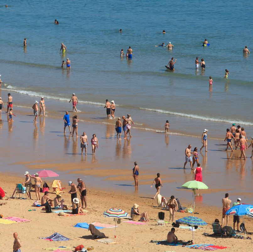 People on the beach using umbrellas and sun hats