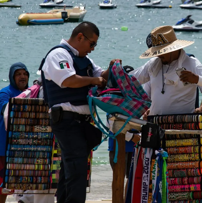 Police officer inspecting vendor backpack on beach
