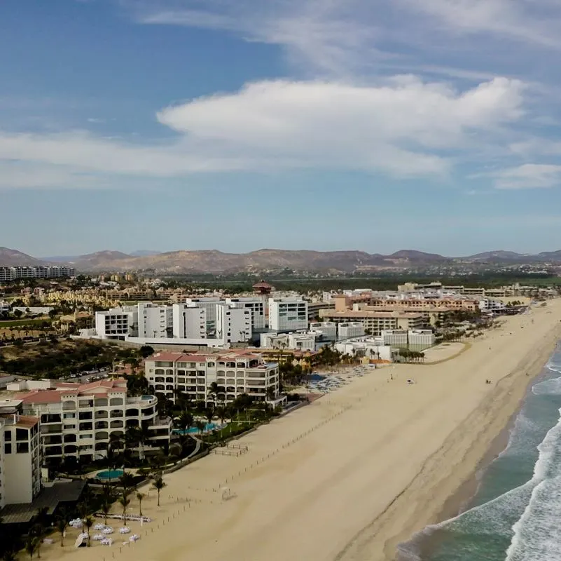 Beachfront properties with mountains behind along long stretch of coastline