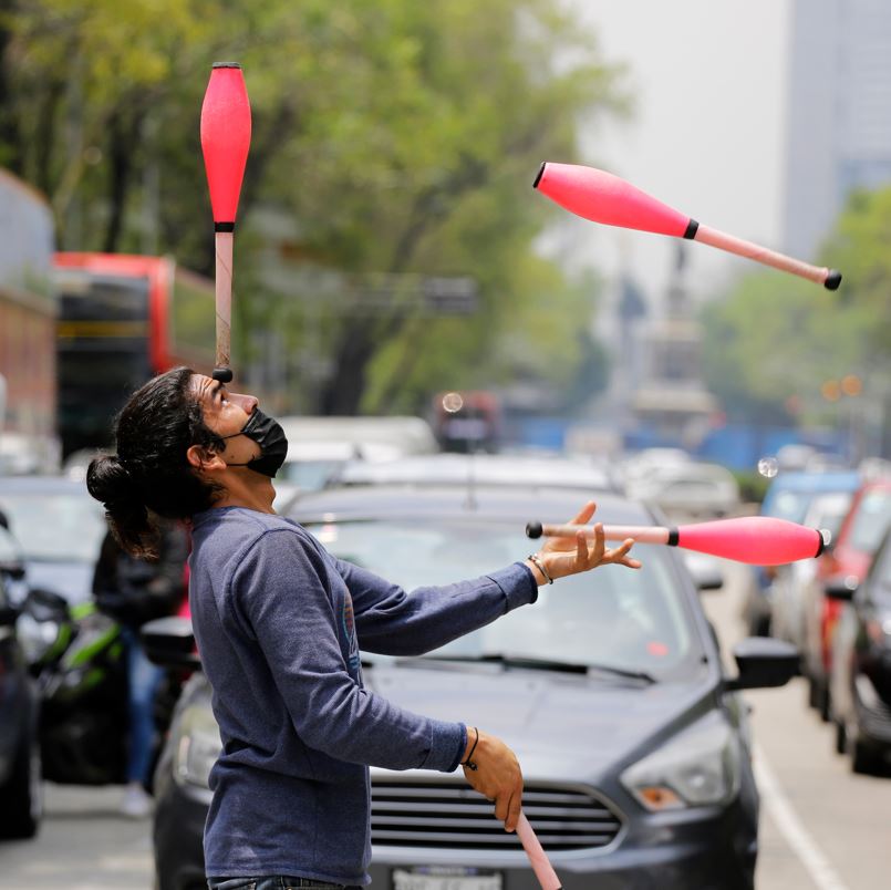 Man on a crosswalk juggling with lots of cars