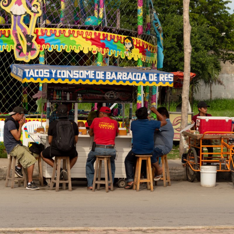 Mexican Street Food Stall with Customers Sitting on Stools