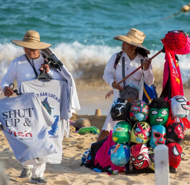 Beach vendors on a beach in Cabo with the water in the background.