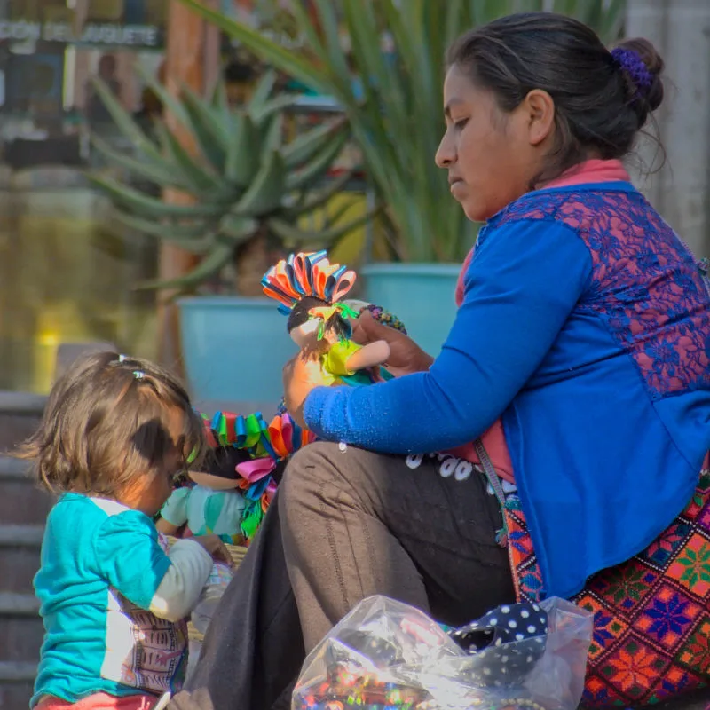Woman and her daughter making dolls to sell on the beach