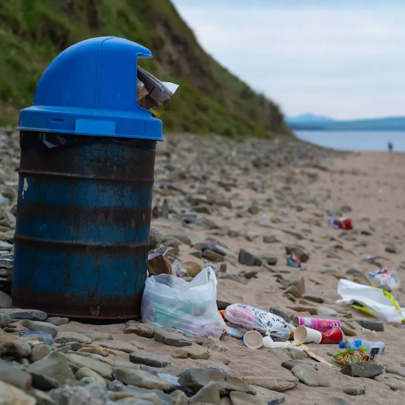 Trash can overflowing with waste on beach