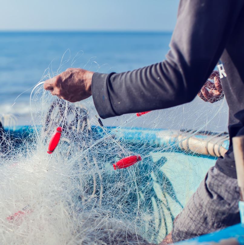 Fisherman with net on a boat out in the ocean