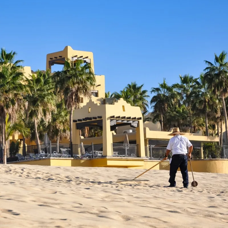 Worker Cleaning Beach with shovel