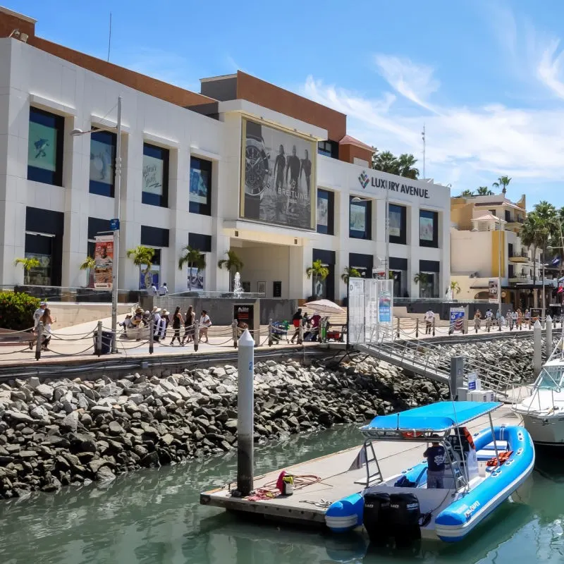 Cabo Marina Shopping center with boats in the water and people walking around.