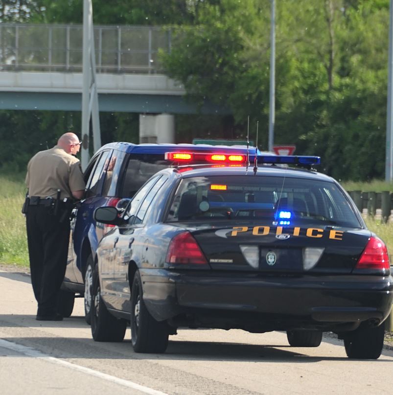 Police officer stopping a car on the side of the highway to write a ticket