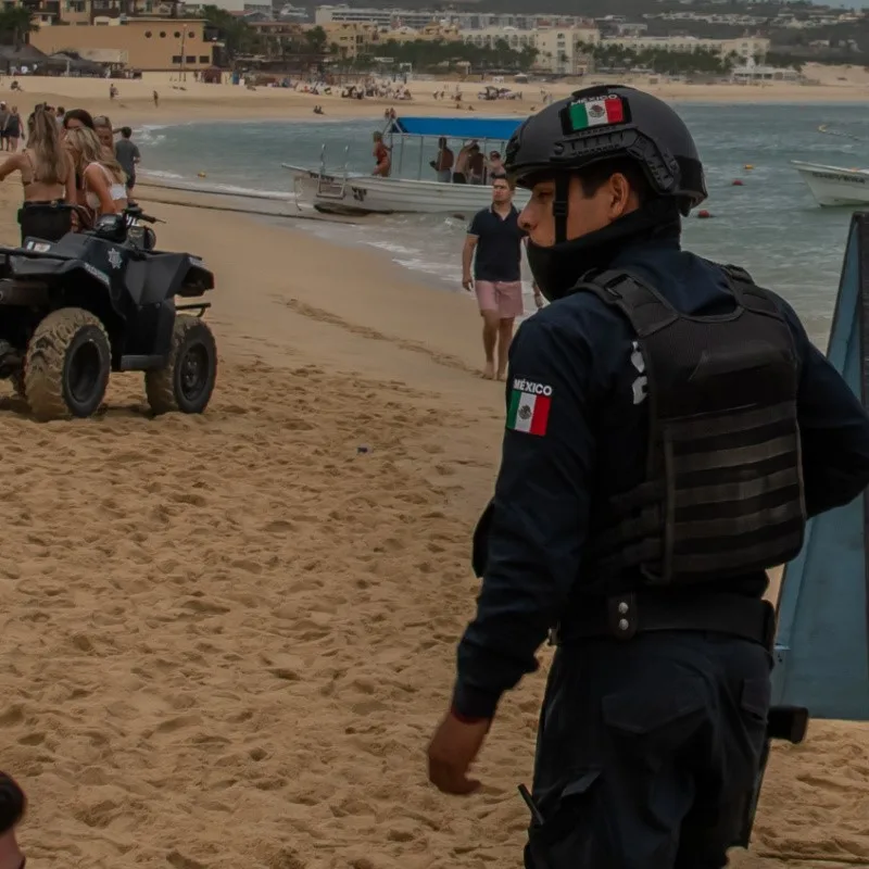 Armed Guard on the Beach Near Hotels in Cabo with tourists on the beach.