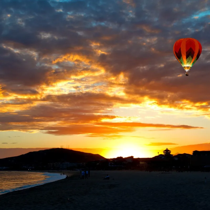 Cabo Beach at Sunset with a beautiful hot air balloon in the sky.