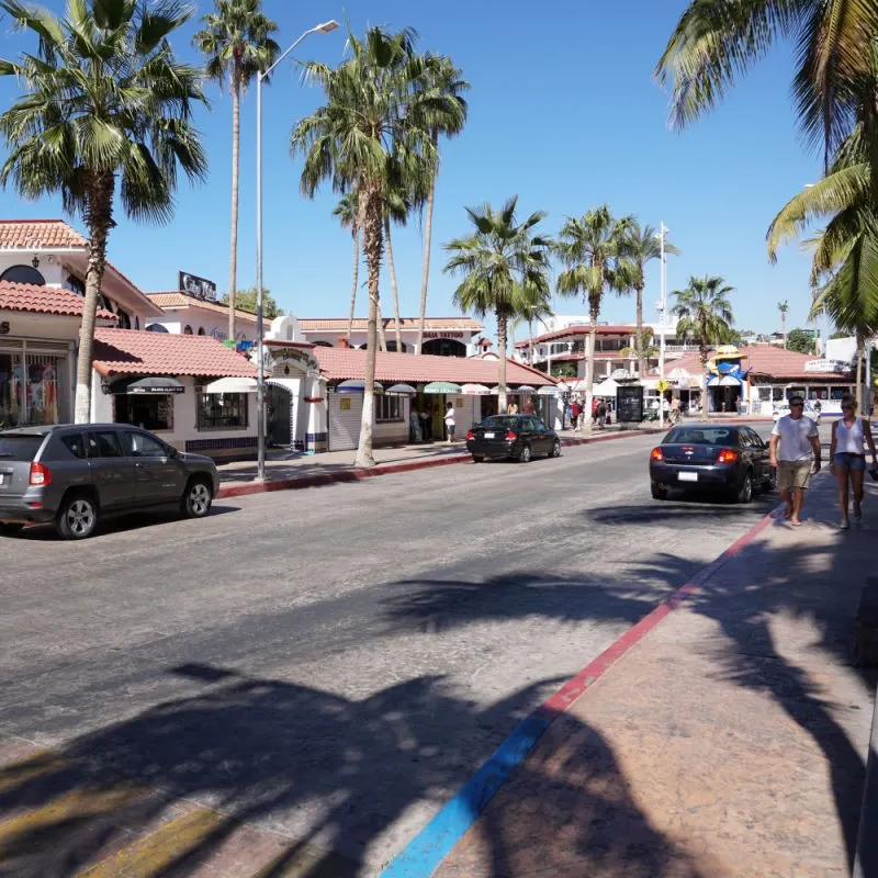 Cabo San Lucas Street with Cars and Tourists On It.