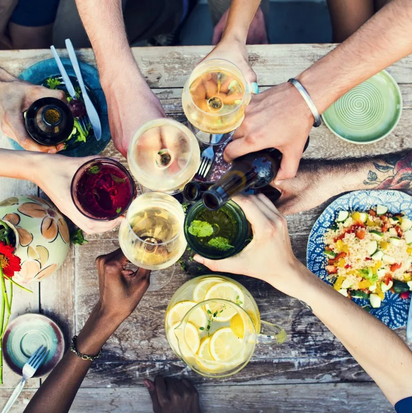 Friends toasting wine over food