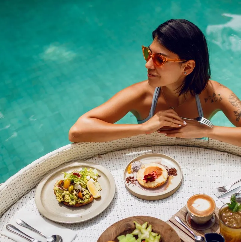 Lady with a tattoo having a large breakfast in the pool