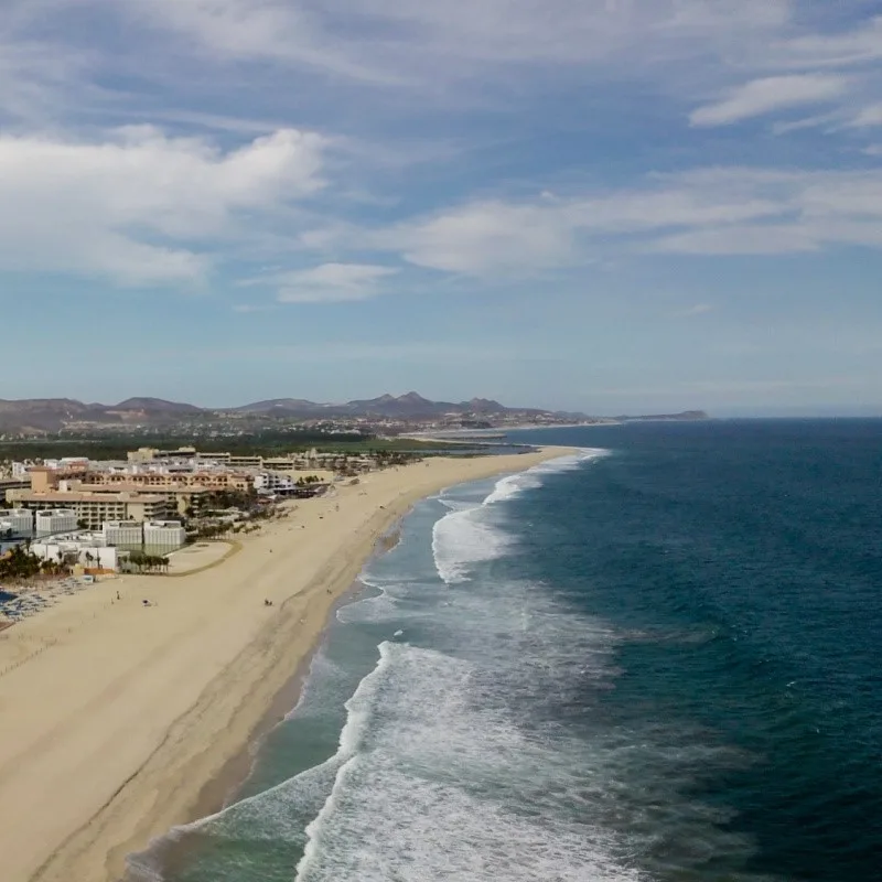 Los Cabos Coastline with a beautiful sandy beach and hotels in the background.