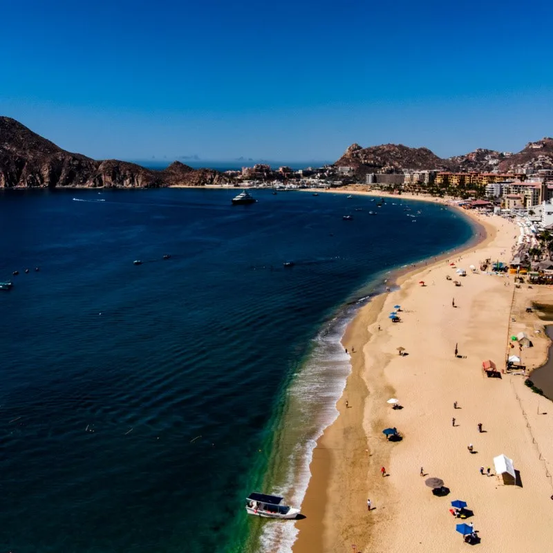 Medano Beach filled with tourists and resorts in the background.