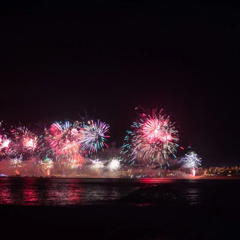 New Year's in Los Cabos with fireworks in the background and a distant view of the city.