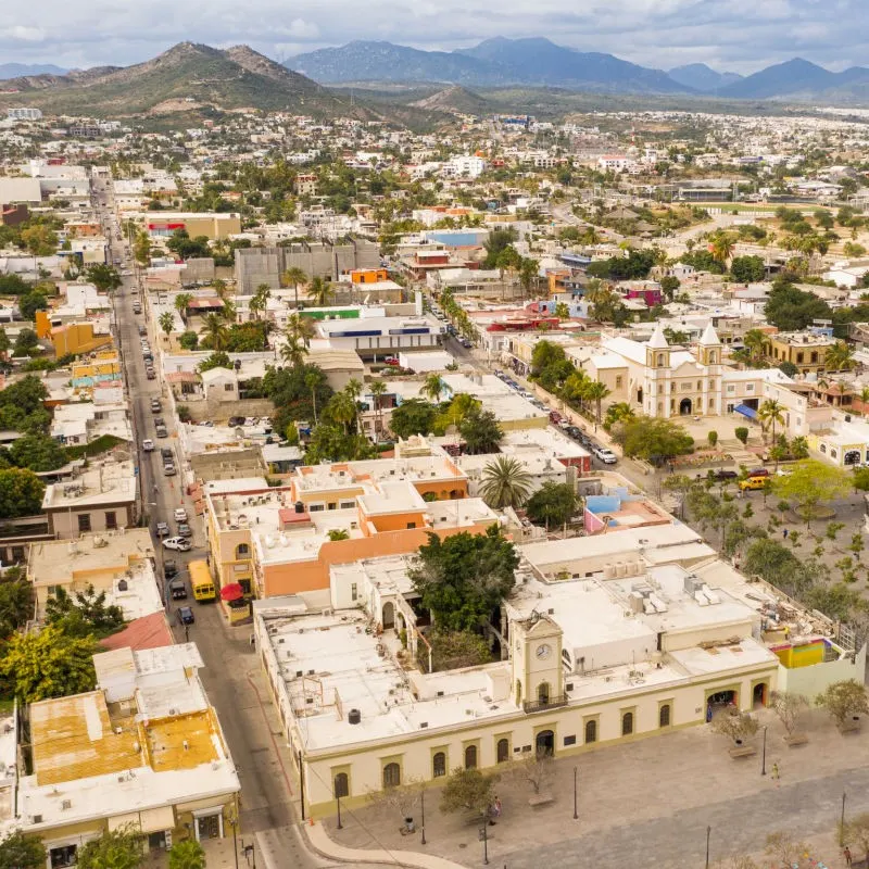 San Jose del Cabo City with buildings, greenery, and hills in the background.