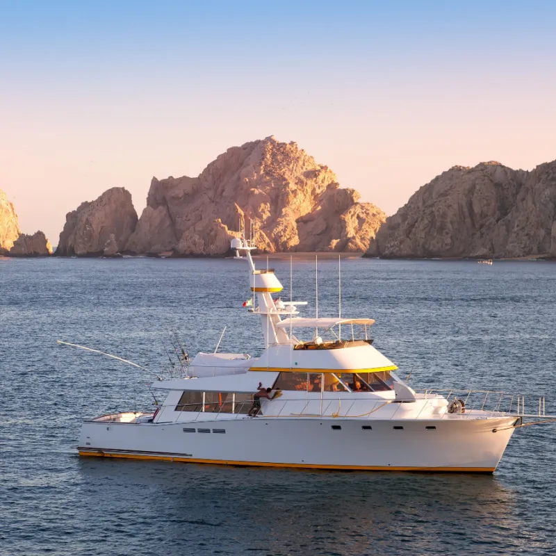 yacht navigating through the Cabo bay at sunset