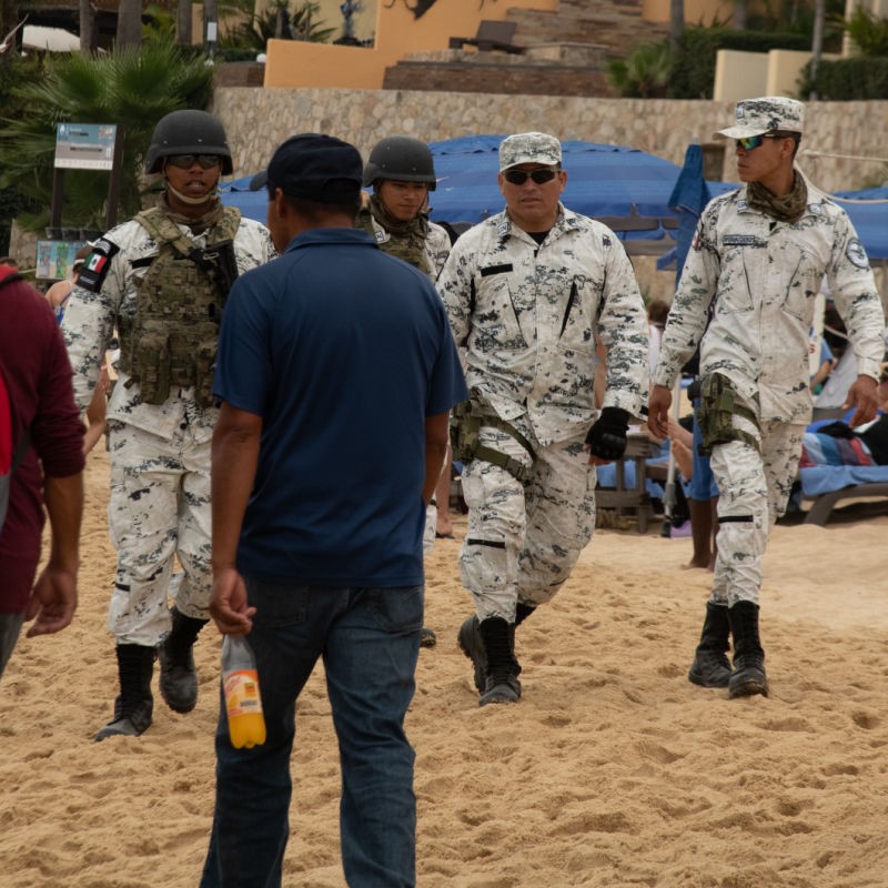 Armed Guards in Cabo on the beach with tourists all around.