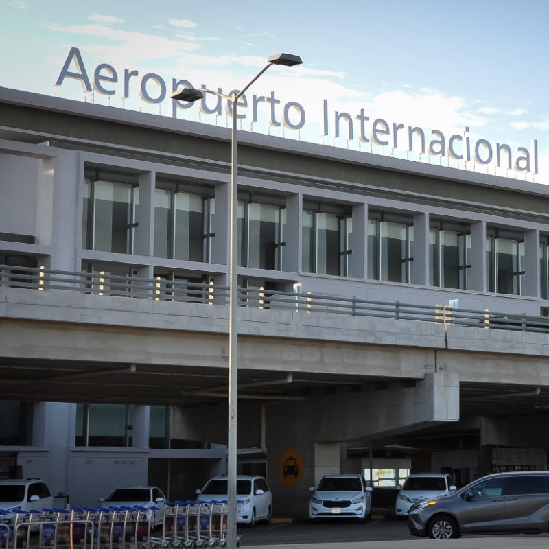 Los Cabos Airport with vehicles parked out front.