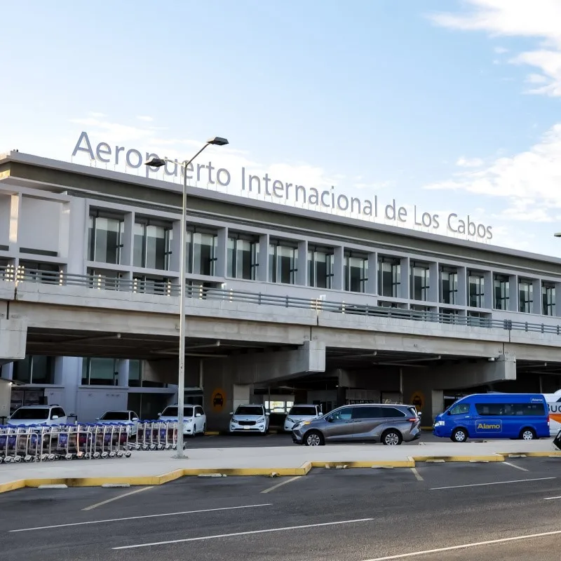 Los Cabos International Airport with cars and an Alamo van parked out front.