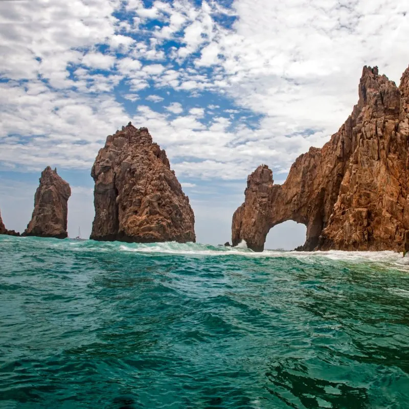The Arch of Cabo San Lucas with a cloudy blue sky above.