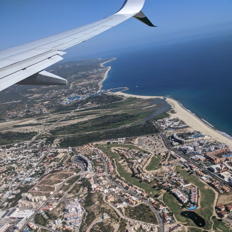 Aerial View of Cabo San Lucas From an Airplane with a view of land and sea.